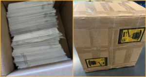 The image shows a box containing stacks of white paper and a separate box with warning labels, possibly indicating fragile or hazardous contents.