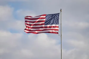 The American flag waves proudly against a backdrop of a cloudy sky.