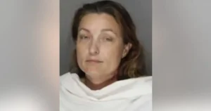 The image appears to be a mugshot of a person wearing a white garment, with a plain background.