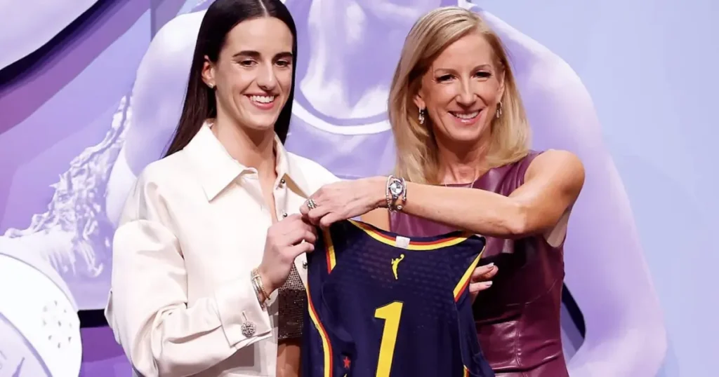 Two women are presenting a sports jersey with the number 1 on it, smiling and posing for the camera.