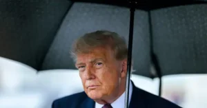 The image shows a person holding an umbrella, with a serious expression on their face.