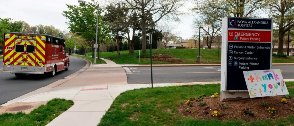 An ambulance is seen driving past the entrance of Inova Alexandria Hospital, with a sign thanking healthcare workers.
