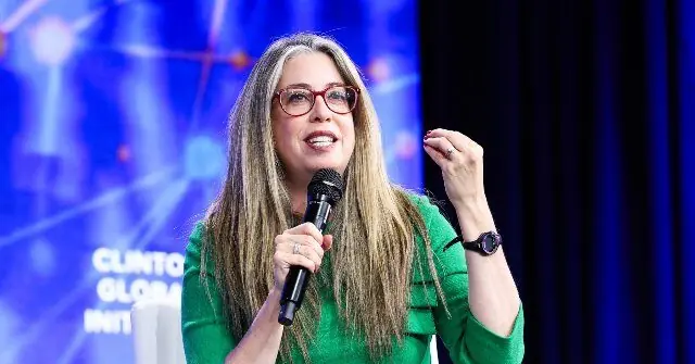 A woman with long dreadlocks and glasses is speaking into a microphone at a Clinton Global Initiative event.