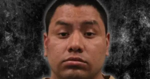The image appears to be a mugshot of a person against a textured background.