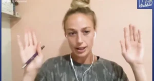 A person is holding a pen and gesturing with their hands while wearing earphones.