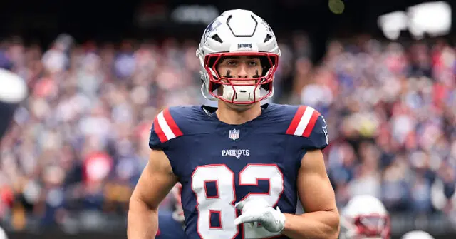 The image shows a football player wearing a New England Patriots uniform with the number 82, standing on the field during a game.
