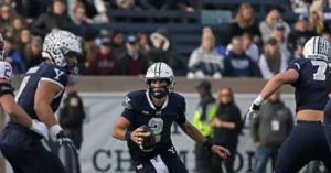 A Yale football player in a dark uniform with the number 2 is preparing to throw the ball during a game.