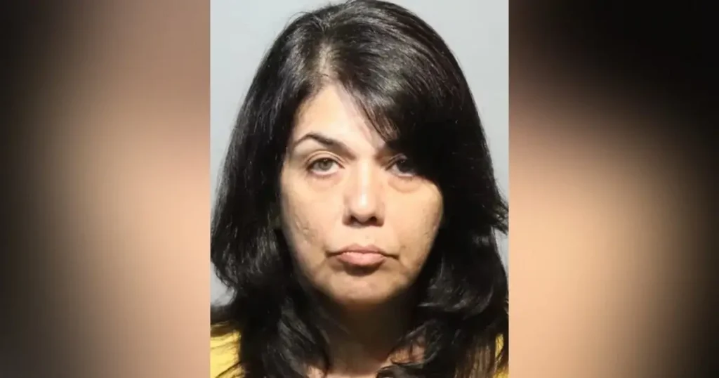 The image appears to be a mugshot of a woman with long dark hair, wearing a yellow top.