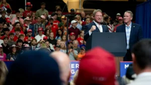 A politician stands at a podium addressing a large crowd at a campaign rally.