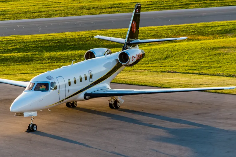 A private jet is parked on a runway with a grassy field in the background.