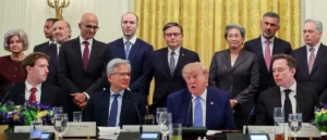 The photo shows a group of business leaders and officials seated at a table with President Trump, in what appears to be a formal meeting or discussion.