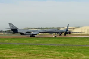A military aircraft is taxiing on a runway at an airfield.