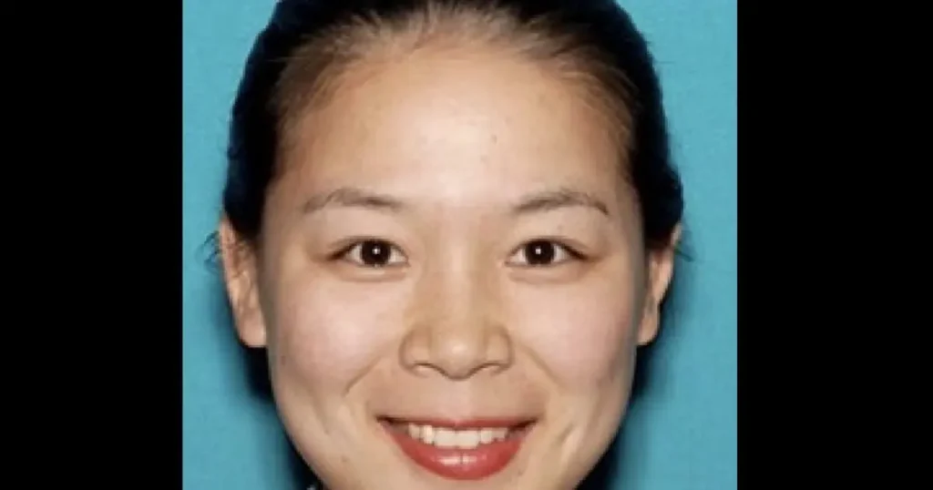 The image shows a person with a neutral expression against a solid blue background.