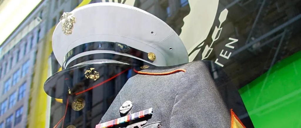 The image shows a close-up of a military uniform and hat, adorned with medals and insignia, displayed in a public setting.