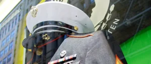 The image shows a close-up of a military uniform and hat, adorned with medals and insignia, displayed in a public setting.