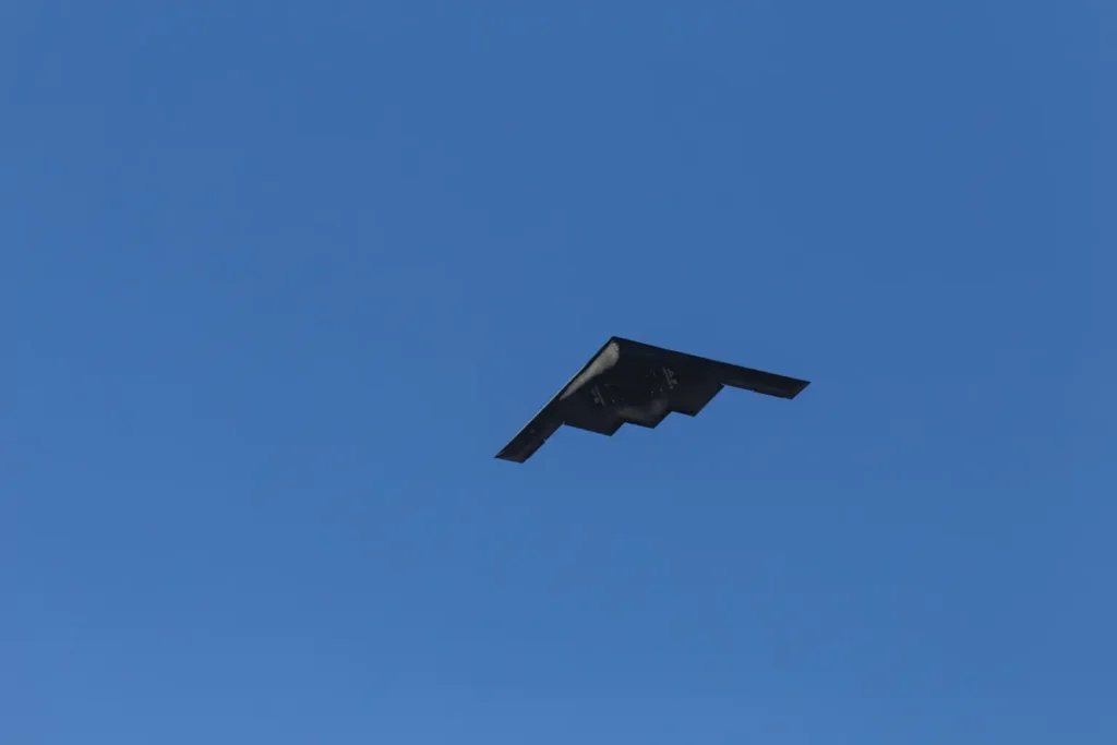A stealth aircraft is captured flying against a clear blue sky.
