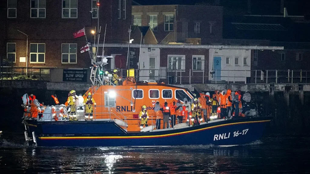 An RNLI lifeboat crew is returning to the dock after a rescue operation at night.