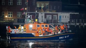 An RNLI lifeboat crew is returning to the dock after a rescue operation at night.