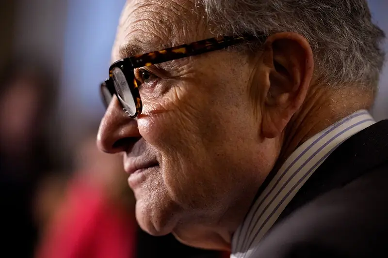 The image shows a close-up of a person wearing glasses and a striped shirt, with a blurred background.