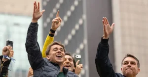 A group of people celebrate and raise their hands in the air, possibly in a public gathering or event.