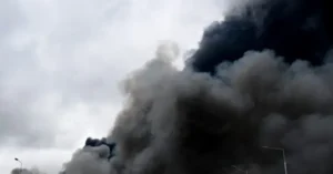 The image shows a large plume of smoke rising into the sky, indicating a significant event or incident, possibly a fire or explosion.