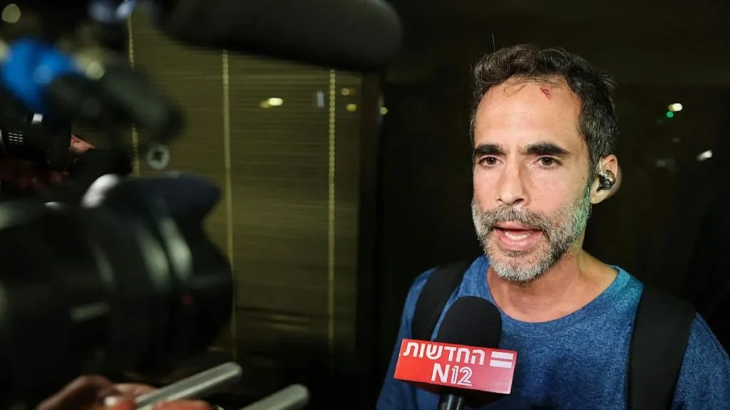 A man is being interviewed by a news reporter, with a microphone from "N12" visible in the foreground.