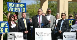 A group of people, including a man at a podium, are advocating for voter ID requirements in California.