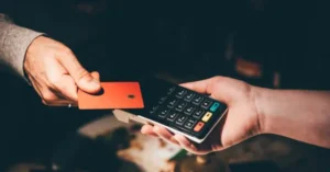 A person is using a credit card to make a payment at a point-of-sale terminal.