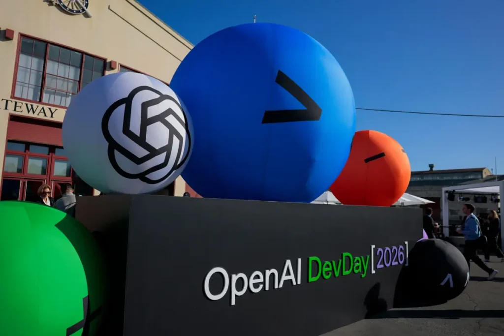 The image shows a sign for "OpenAI DevDay 2026" with large inflatable spheres in various colors and designs, indicating a tech event.