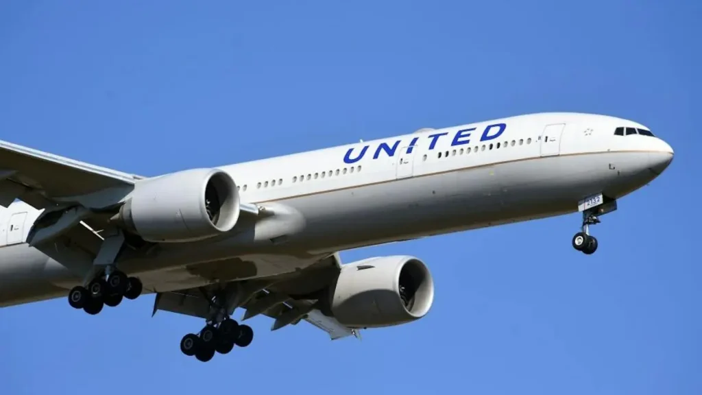 A United Airlines aircraft is captured in flight against a clear blue sky.