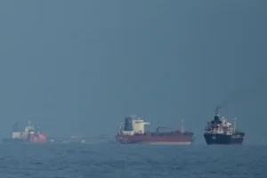 The image shows a group of ships sailing on calm waters under a clear sky.