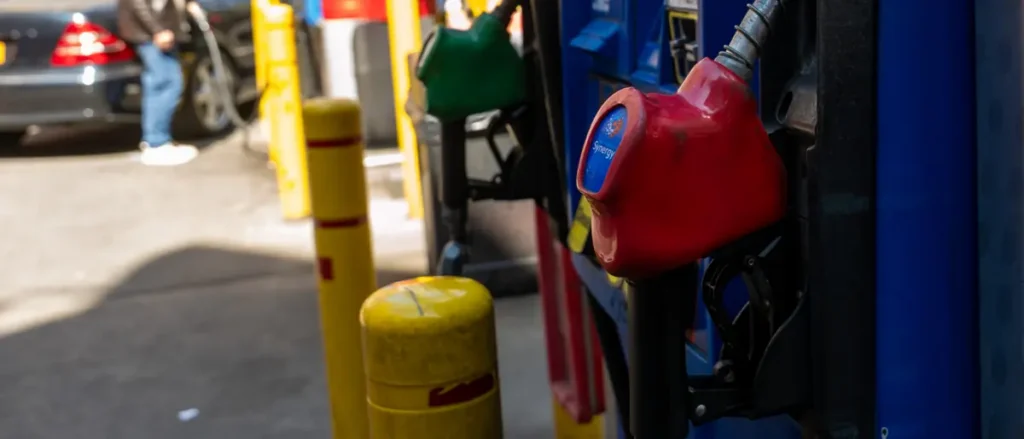 A close-up of a red fuel nozzle at a gas station pump.