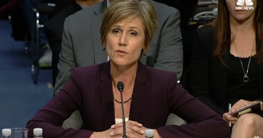 A woman in a professional setting speaks into a microphone during a formal event.
