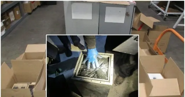 The image shows a person wearing gloves handling a container with what appears to be a wrapped object, possibly for secure transportation or storage.