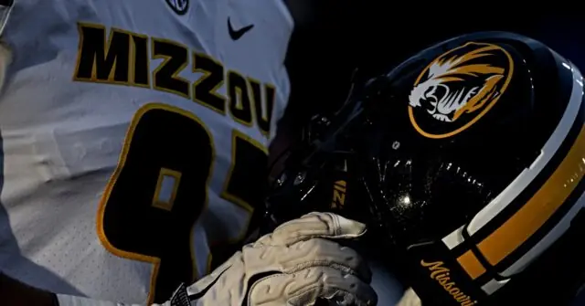The image shows a close-up of a Missouri football player holding a helmet, wearing a jersey with the number 91.