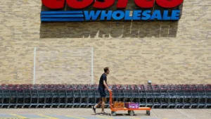 A man pushes a cart with boxes in front of a Costco Wholesale store.