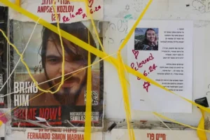 The image shows posters with messages and photos, including one with the text "BRING HIM HOME NOW!" and another with a release date, tied with yellow ribbons.