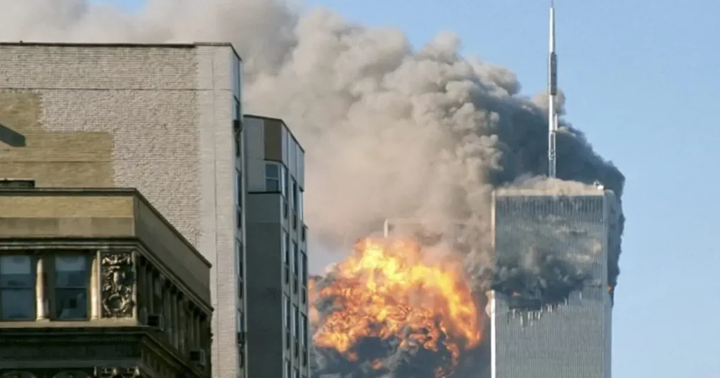 The image shows a large plume of smoke and flames engulfing a tall building, indicating a significant fire or explosion.