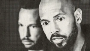 The image is a halftone-style news photo featuring two individuals, one of whom is bald and has a beard.