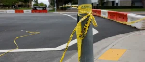 A yellow caution tape is wrapped around a pole at a construction site, indicating a restricted or hazardous area.