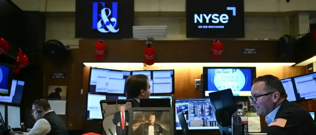 The image shows a trading floor at the New York Stock Exchange (NYSE) with traders working at their stations, some wearing red hats, and monitors displaying financial data.