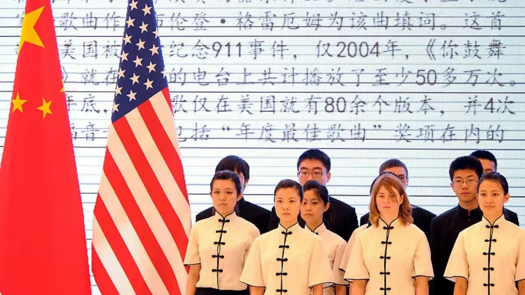 A group of individuals in traditional attire stands in front of the flags of China and the United States, with a backdrop of Chinese text.