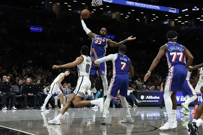 A basketball player in a blue jersey with the number 23 leaps to shoot the ball during a game.