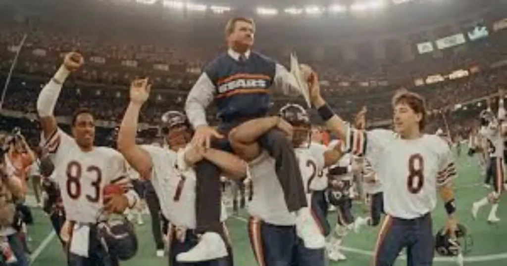A jubilant Chicago Bears team celebrates a victory, lifting their coach onto their shoulders in a moment of triumph.