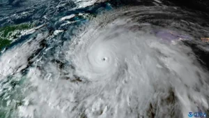 This satellite image shows a powerful hurricane with a well-defined eye and surrounding swirling clouds, indicating intense weather activity.