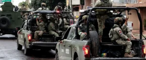 The image shows a group of soldiers in military vehicles, likely part of a military operation or patrol, as indicated by their uniforms and equipment.
